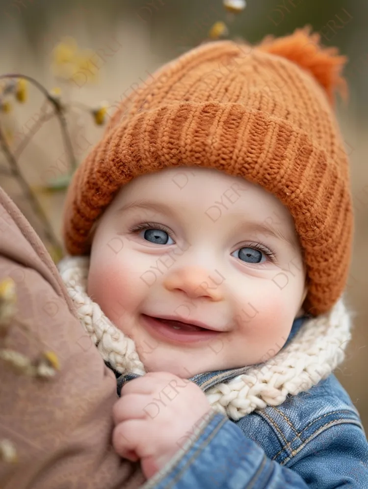 Bebê sorridente com gorro laranja e cachecol, em ambiente natural